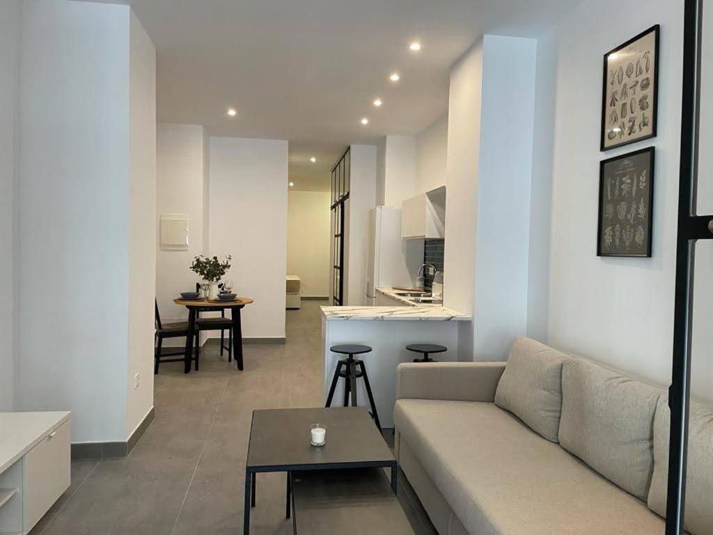 ein weißes Wohnzimmer mit einem Sofa und einer Küche in der Unterkunft COMPLEJO PINTA18 AT1, AT2 y AT3 in Sevilla