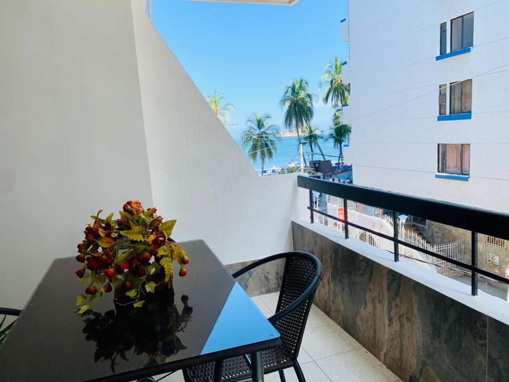 a table with a vase of flowers on a balcony at Santa Marta Apartamentos - Palanoa in Santa Marta