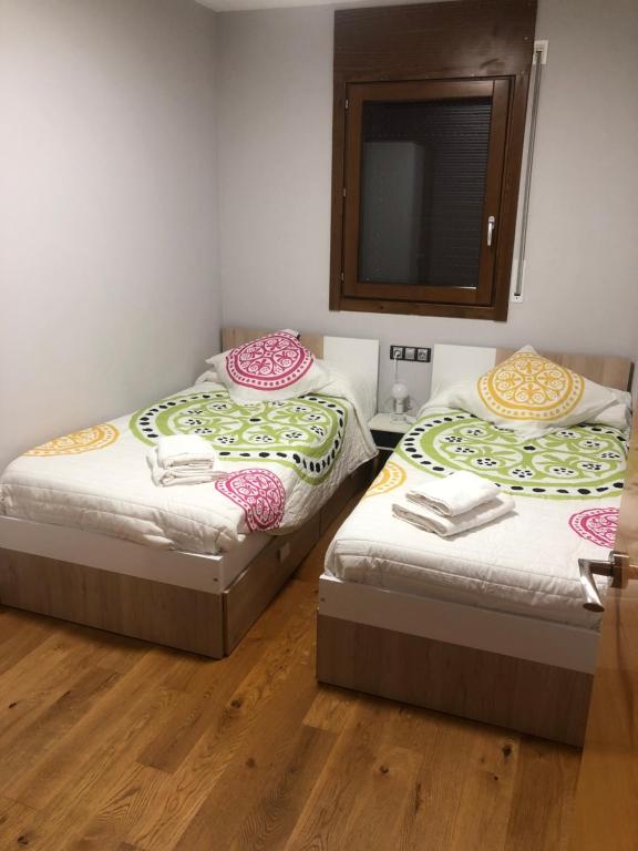 two twin beds in a room with a mirror at Precioso apartamento con piscina, ideal familias! in Sort
