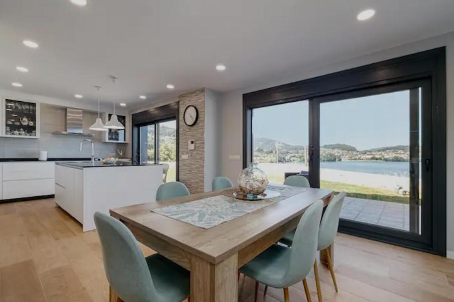 eine Küche und ein Esszimmer mit einem Holztisch und Stühlen in der Unterkunft Casa nueva con piscina y vistas al mar in Vilaboa