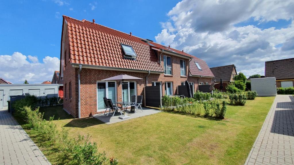 a brick house with a yard in front of it at Ferienhaus Sielperle in Carolinensiel