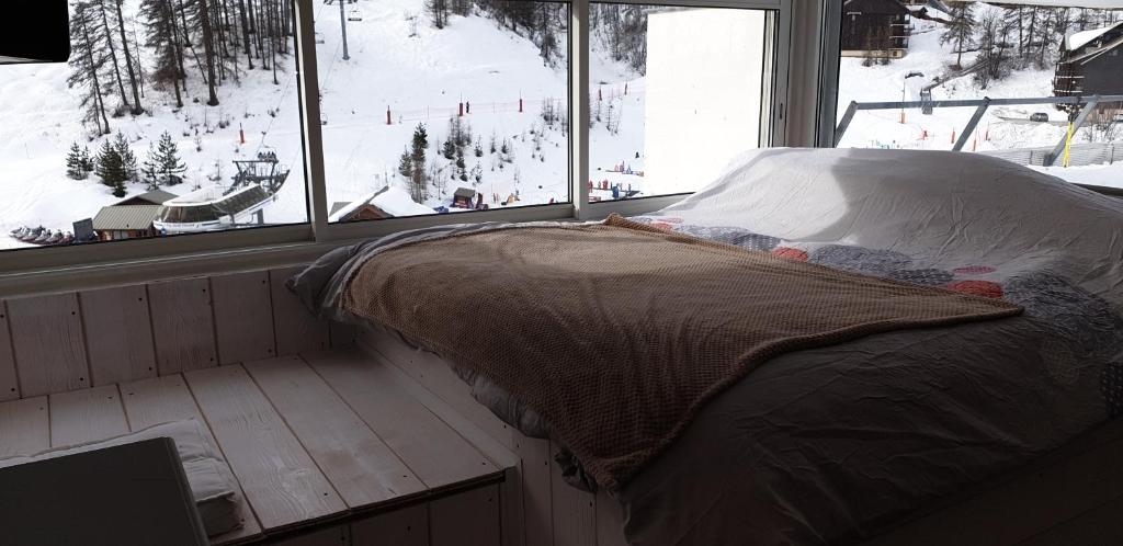 a bed in a room with a view of a ski slope at appartement pendine 1 plein sud 53m2 in Puy-Saint-Vincent