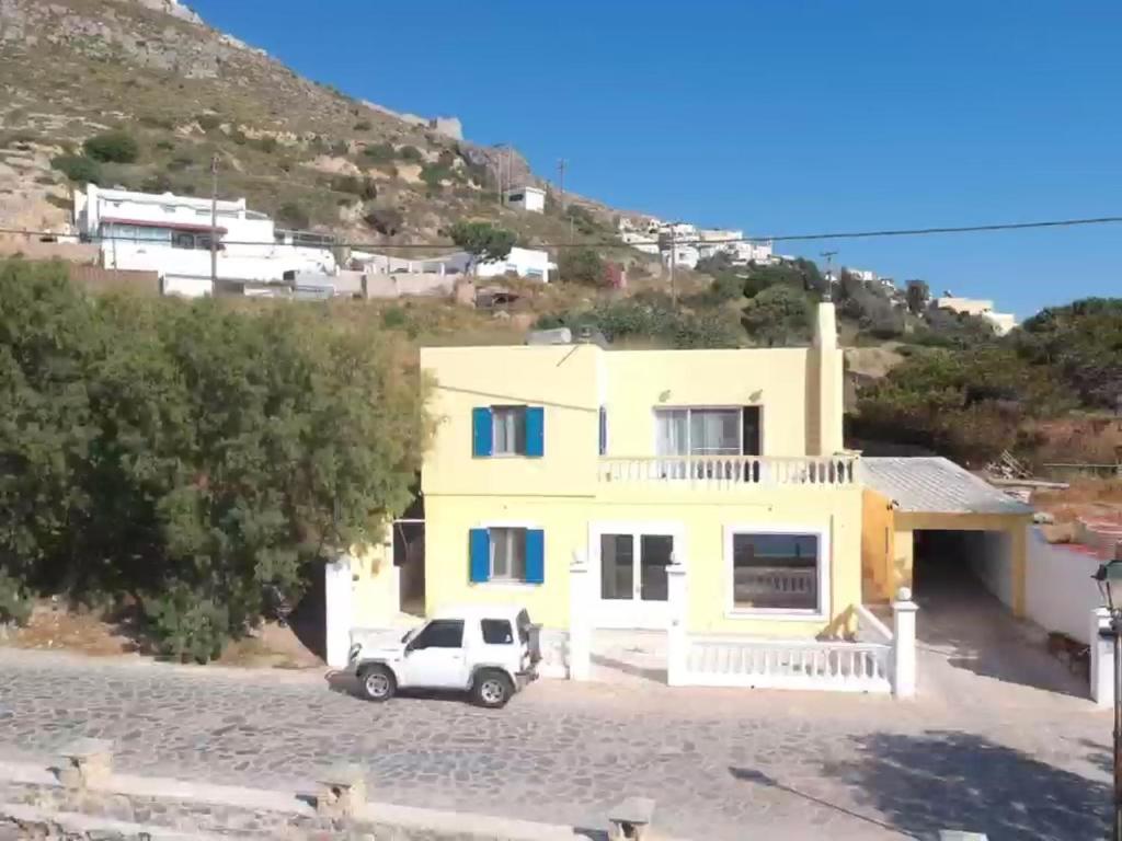 a white car parked in front of a yellow house at The Condo Palace in Agia Marina in Agia Marina