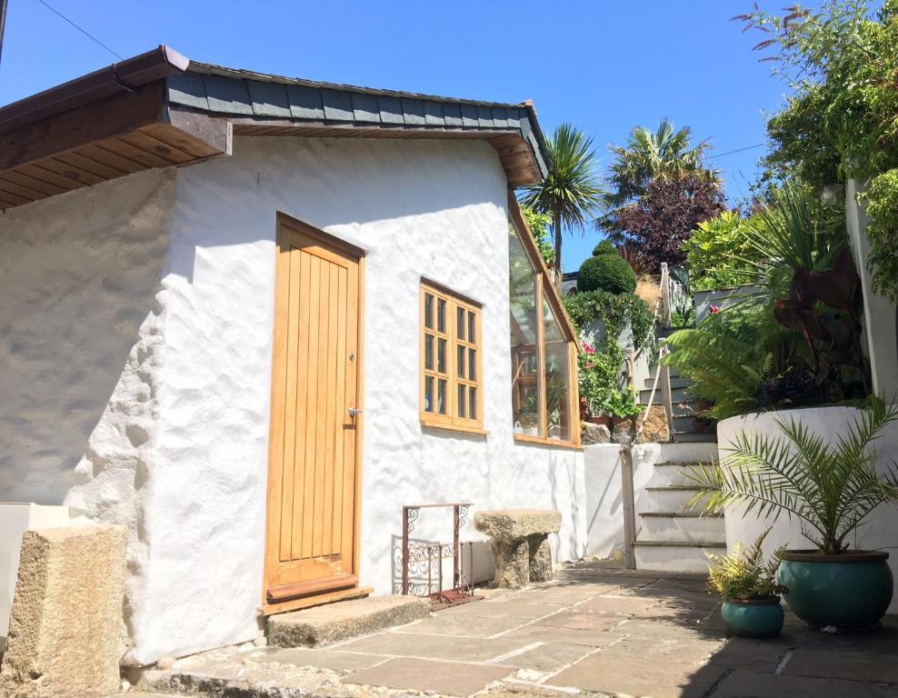 a small white house with a wooden door at Quay Courtyard in Charlestown