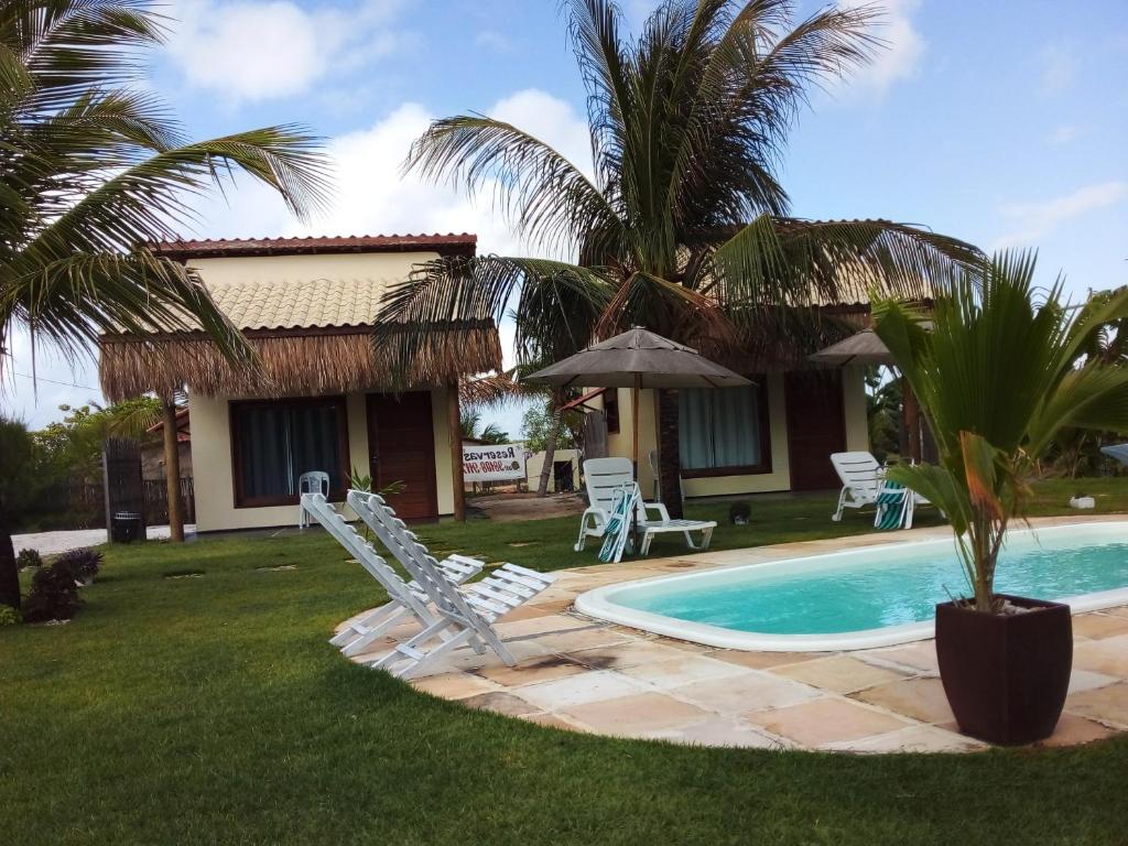 uma casa com piscina e cadeiras e uma palmeira em Chalés Ed Moitas em Praia de Moitas