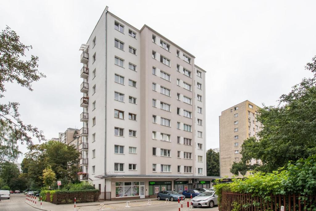 a tall white building with cars parked in a parking lot at Dekart Center View in Warsaw