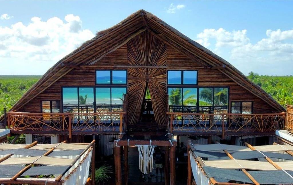 a large wooden house with a deck and windows at Casa Hayhu in Mahahual