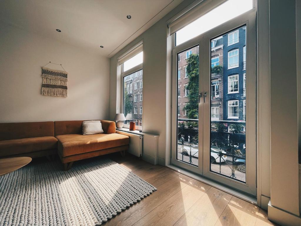 a living room with a couch and a large window at Spacious Designer Duplex next to Central Park in Amsterdam