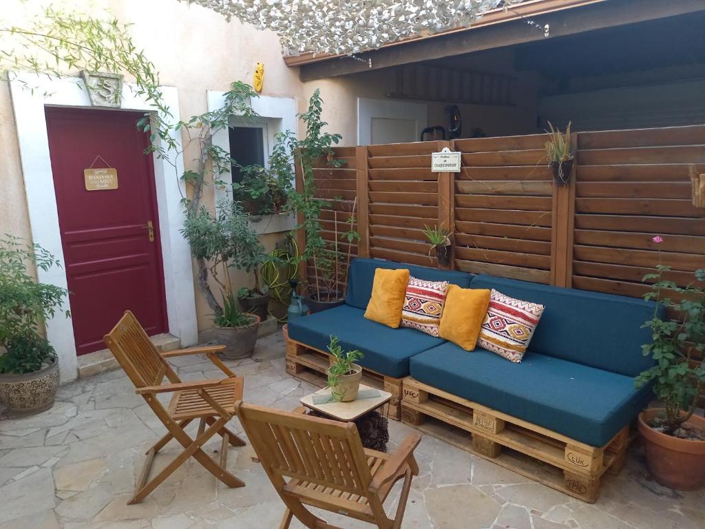 eine blaue Couch auf einer Terrasse mit Stühlen in der Unterkunft studio cosy à 10 minutes de Nîmes in Bouillargues