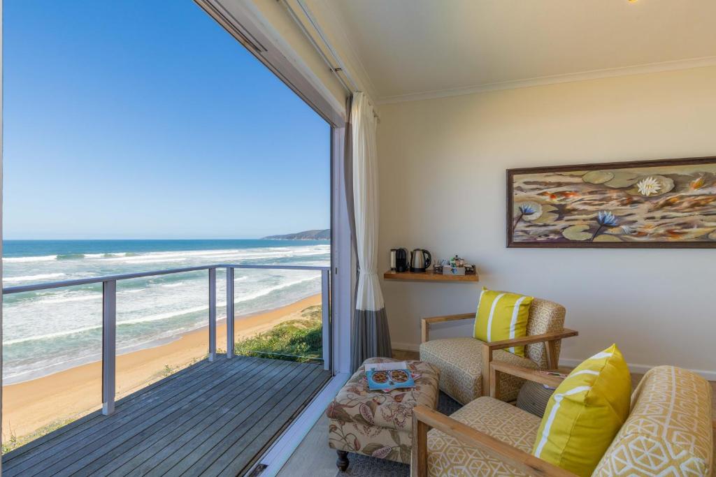 um quarto com uma varanda com vista para a praia em Dune Beach House em Wilderness