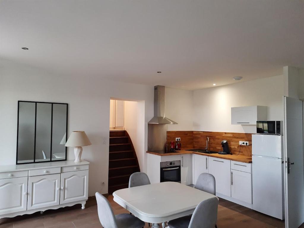 Brouckerque的住宿－LA CLEF DES CHAMPS GITE PERRINE，厨房配有白色橱柜和桌椅