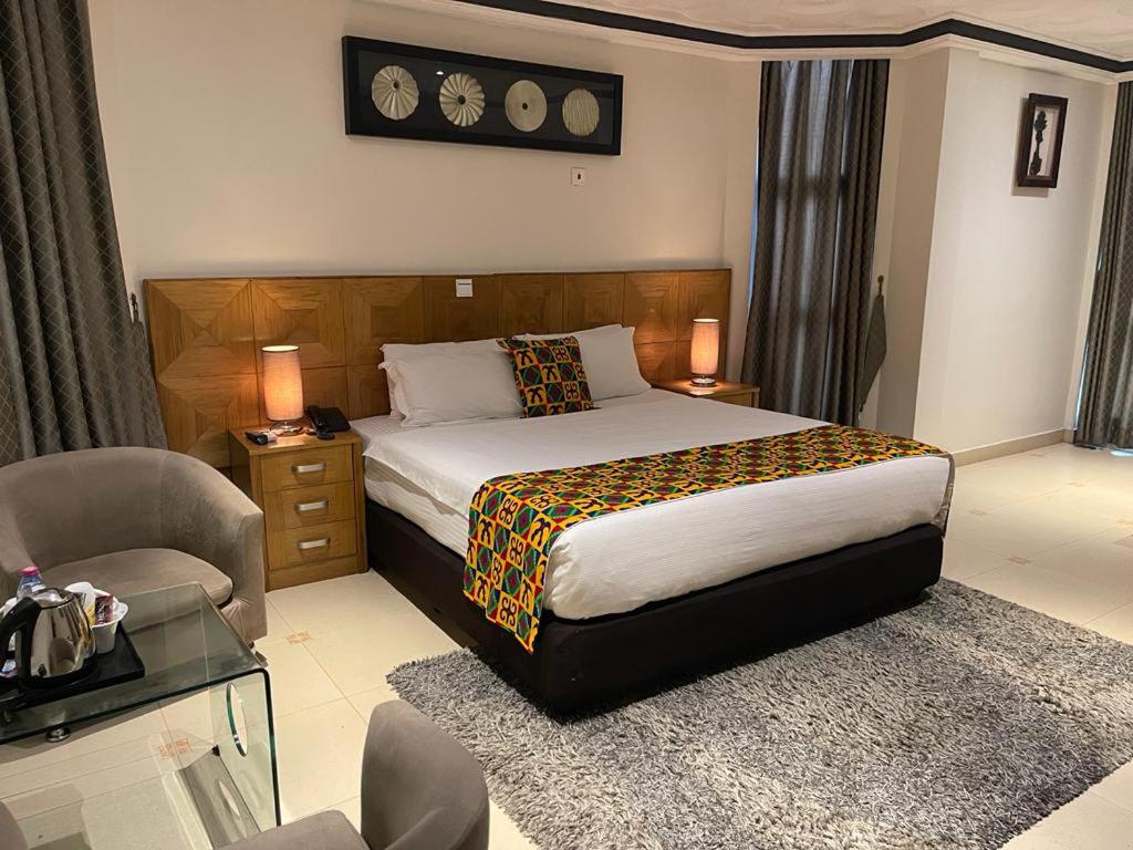 ein Schlafzimmer mit einem Bett, einem Sofa und einem Stuhl in der Unterkunft Airport West Hotel in Accra