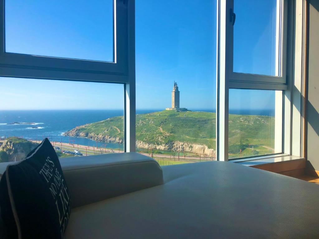 Cette chambre dispose d'un canapé et offre une vue sur un phare. dans l'établissement PARKING, vistas al MAR y tres habitaciones, à La Corogne