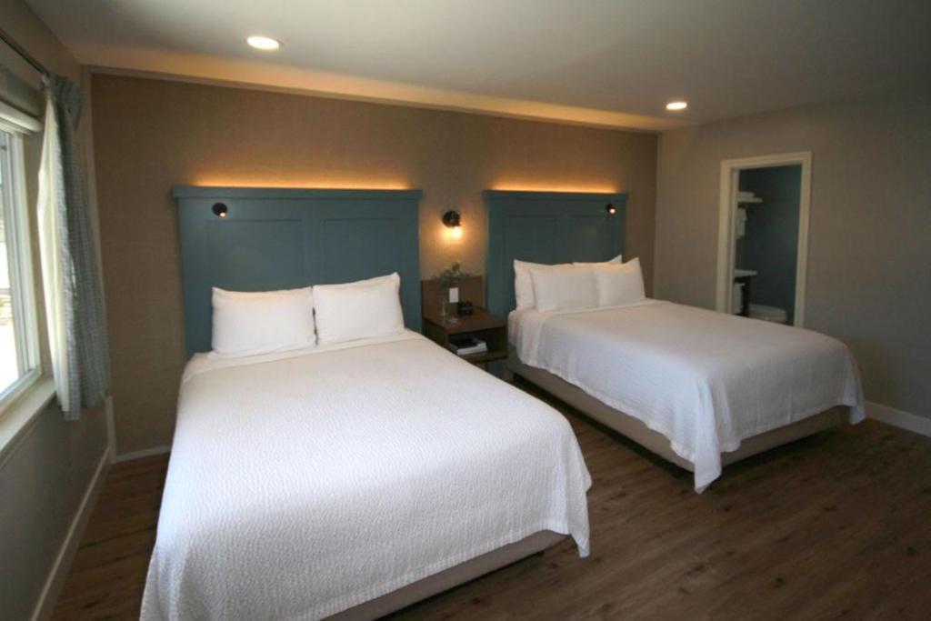 two beds in a hotel room with white sheets at Castle Inn in Cambria