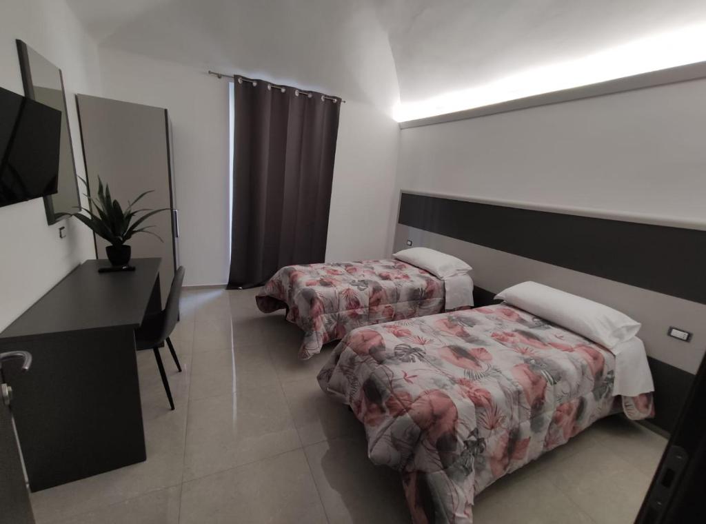 Habitación con 2 camas, escritorio y espejo. en Novara en Novara