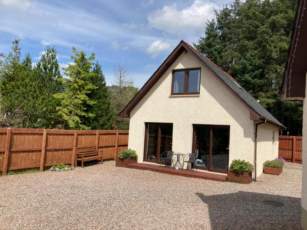 una casa bianca con recinzione e patio di Thistle Do Fort William a Fort William