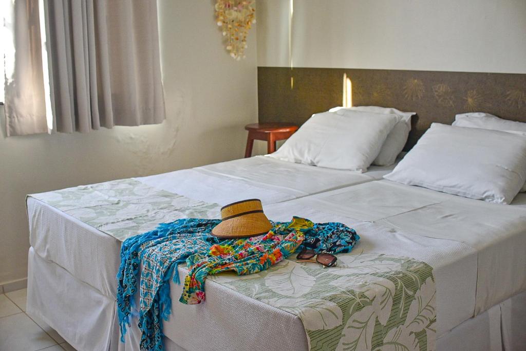 a bed with a hat and a pile of clothing on it at Casa DasCli in Camocim