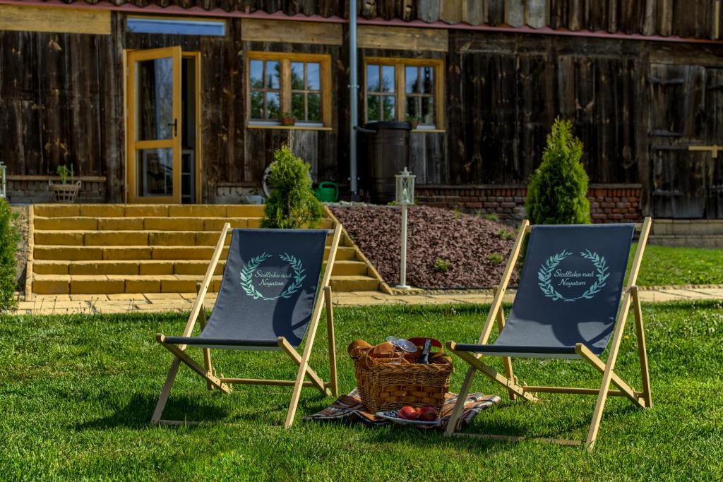 two chairs sitting in the grass in front of a house at Siedlisko nad Nogatem in Jazowa