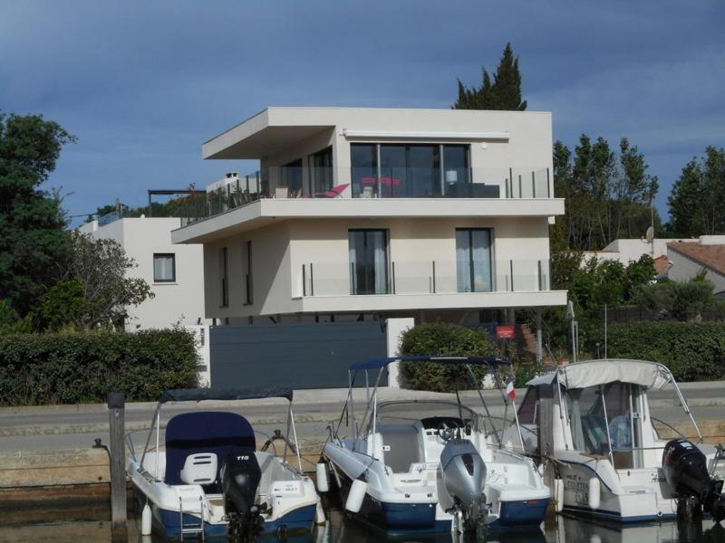 a large house with boats docked in front of it at SUPERBE VILLA VUE MER 4 Etoiles 10 COUCHAGES PISCINE CHAUFFE in La Londe-les-Maures