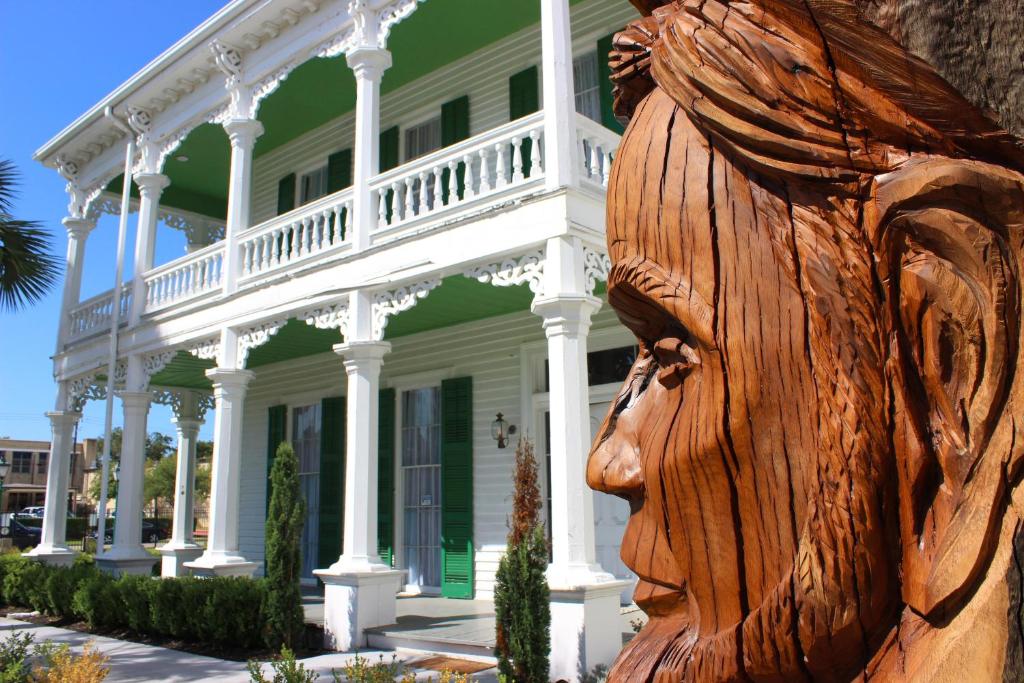 une statue d'une femme devant une maison blanche dans l'établissement The George Manor, à Galveston
