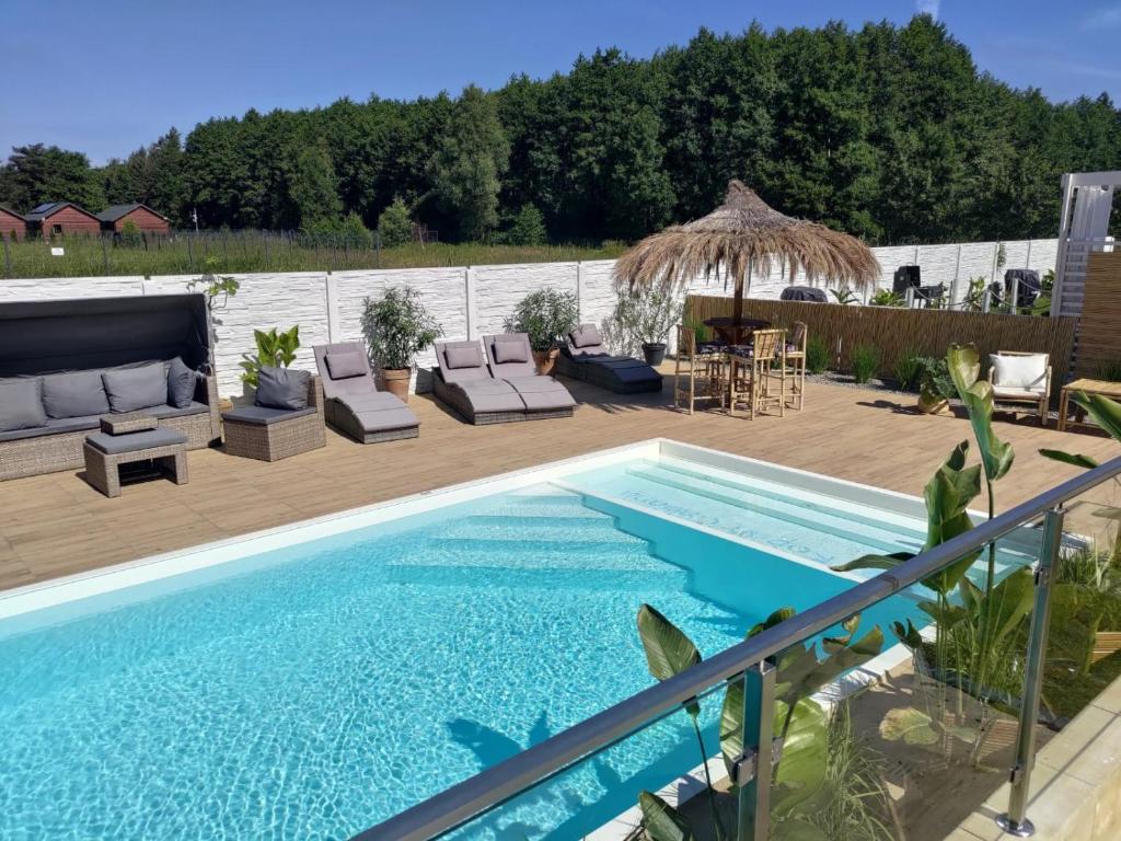 una piscina con sillas y un patio con aiki en Kopań Kabana en Darłowo