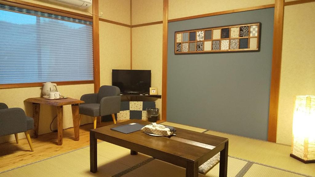 een woonkamer met een tafel en een televisie bij Guest House Nishimura - Vacation STAY 13438 in Kyoto