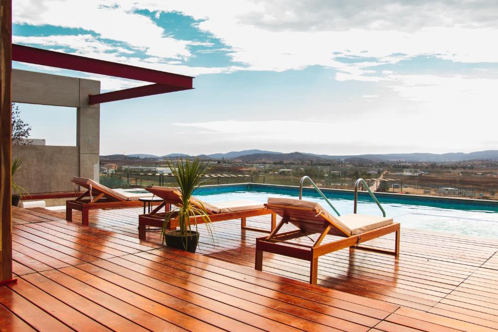 a wooden deck with chairs and a swimming pool at Contemplacion in Valle de Guadalupe