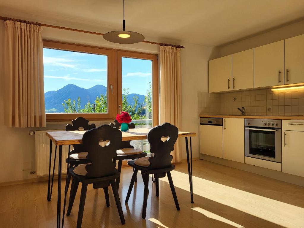 eine Küche mit einem Tisch, 4 Stühlen und einem Fenster in der Unterkunft Wohnung Weitsicht in Ruhpolding
