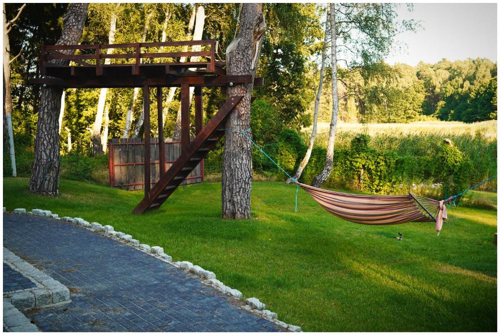 a hammock hanging from two trees in a yard at Domki Loft Park in Skąpe