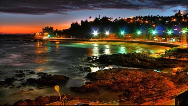 a view of a beach at night with lights at Ondina Praia Apartamento in Salvador