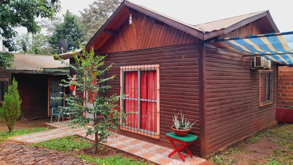 uma pequena casa com uma porta vermelha e um banco verde em Voces De La Selva Misionera em Puerto Iguazú