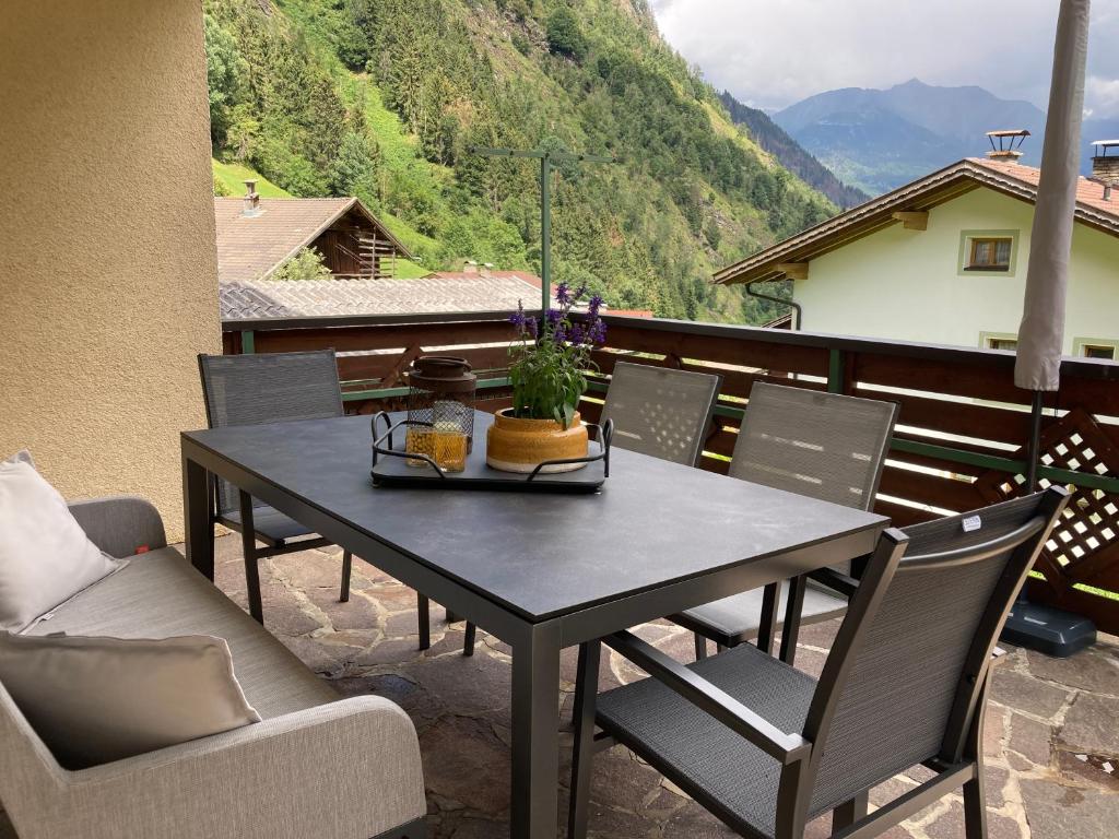 een zwarte tafel en stoelen op een balkon met uitzicht op de bergen bij Haus Waldblick in Hopfgarten in Defereggen