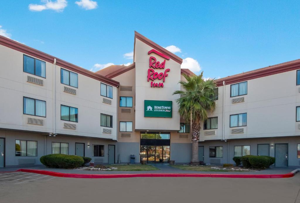 a hotel with a palm tree in front of a building at HomeTowne Studios by Red Roof San Antonio - SeaWorld Northwest in San Antonio
