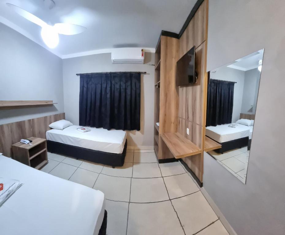 una camera d'albergo con due letti e uno specchio di Hotel Pousadas Club a Sorocaba