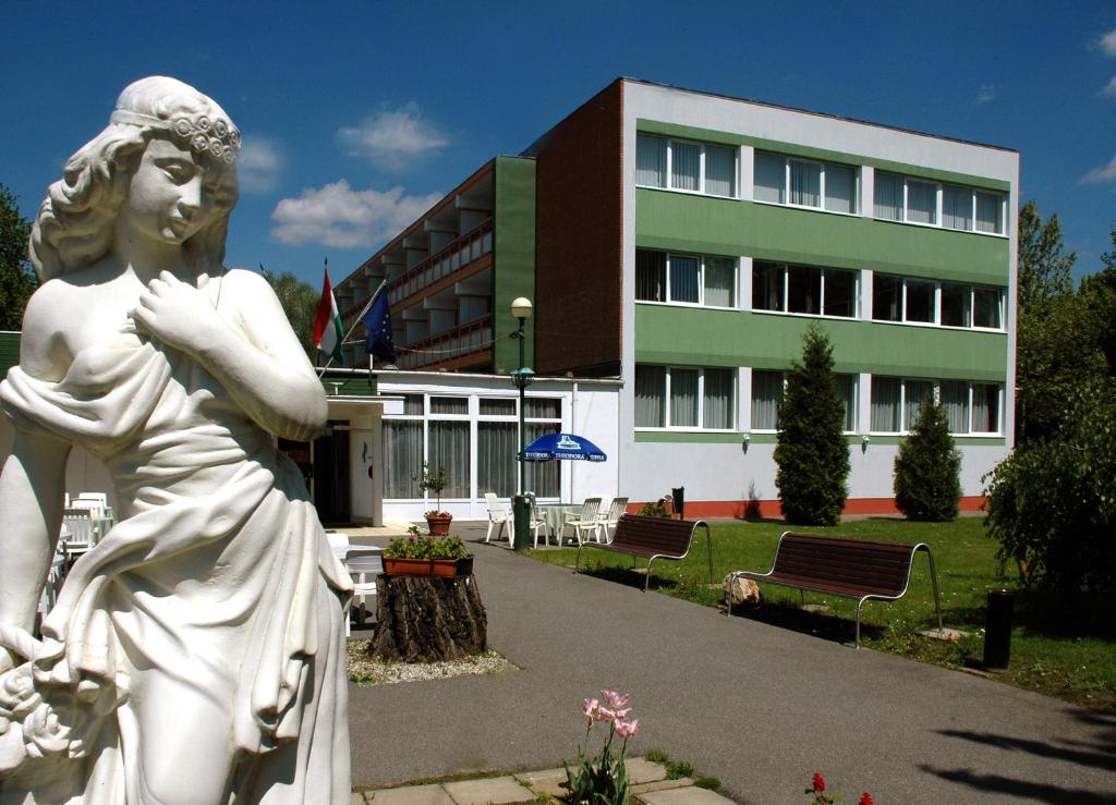 a statue of a woman in front of a building at Komfort Hotel Platan in Harkány