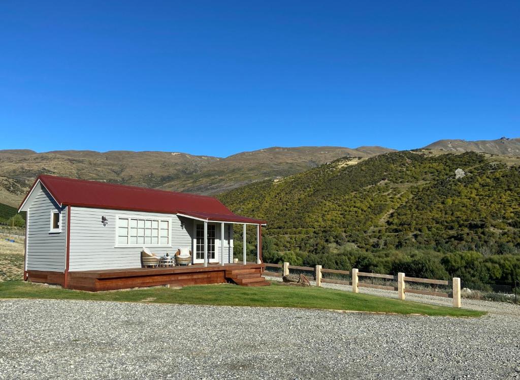 a small white house with a red roof at Rose Creek Cottage in Cromwell