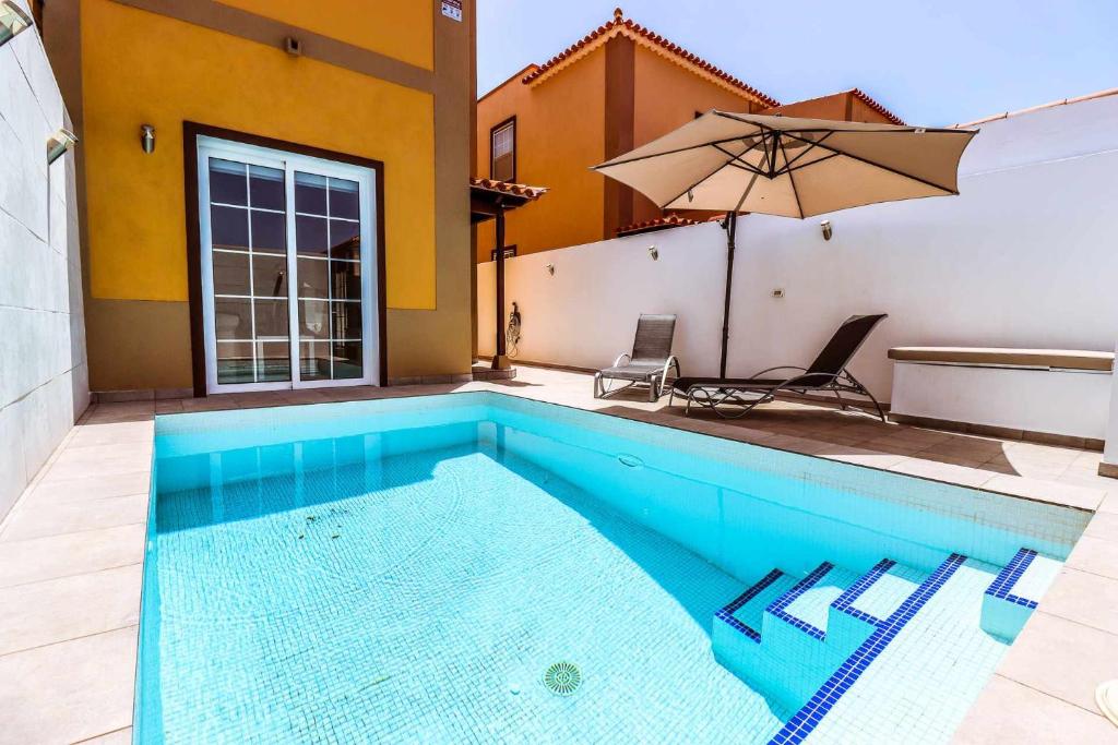 - une piscine avec un parasol à côté d'une maison dans l'établissement Rentaliday Estrella Marazul, à Las Galletas