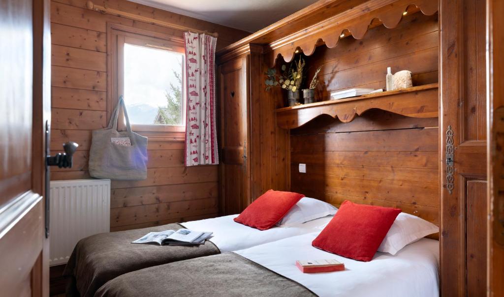 a bedroom with a bed with two red pillows at Résidence Pierre &amp; Vacances Premium Les Alpages de Chantel in Arc 1800