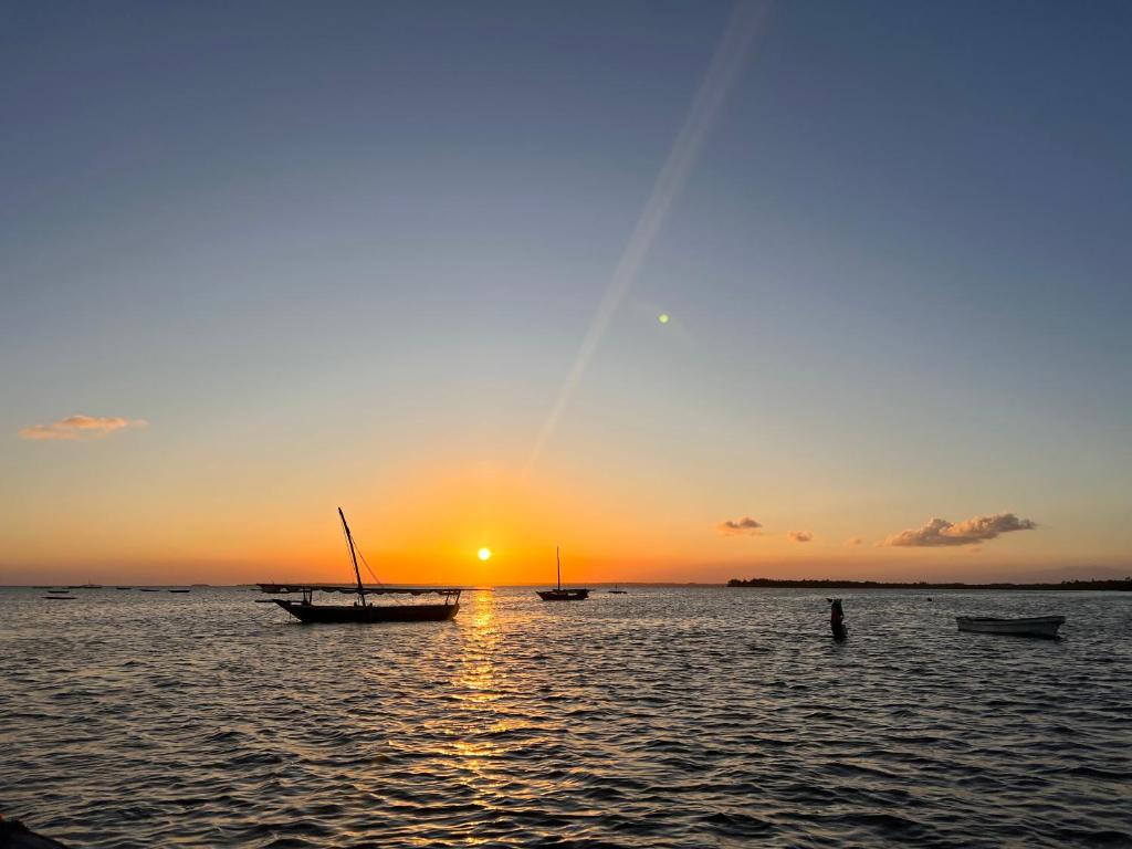 a group of boats in the water at sunset at Sunrise Beach Nungwi in Nungwi