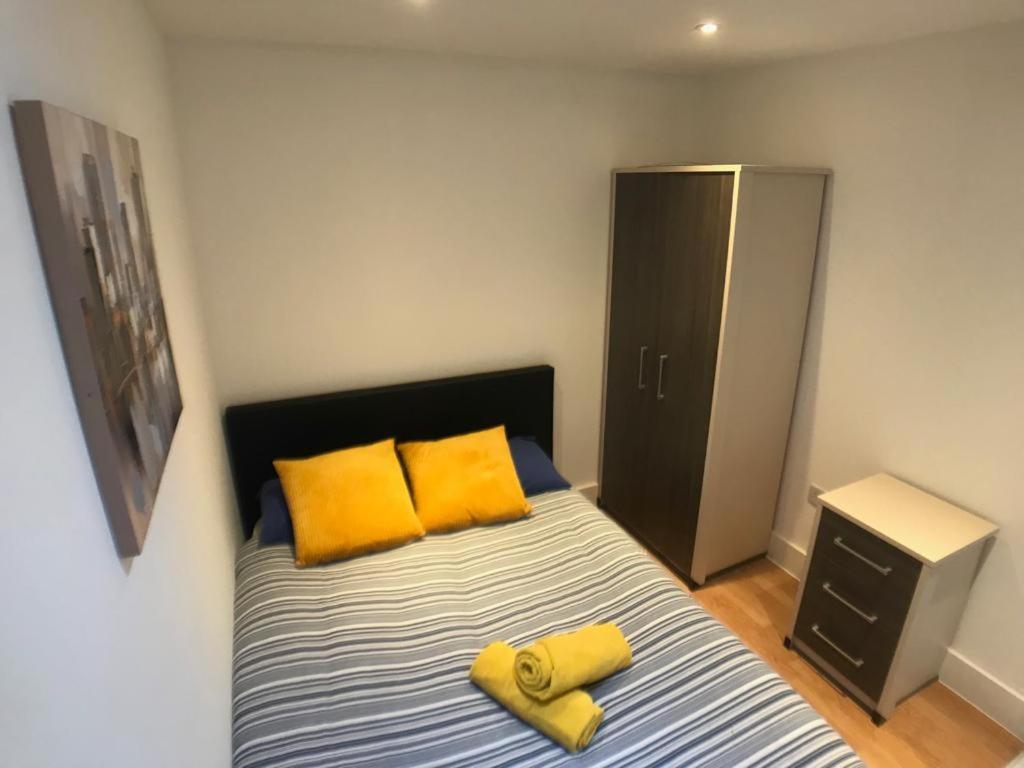 - une chambre avec un lit doté d'oreillers jaunes et d'une armoire dans l'établissement City Sparrow Pad 6, à Londres