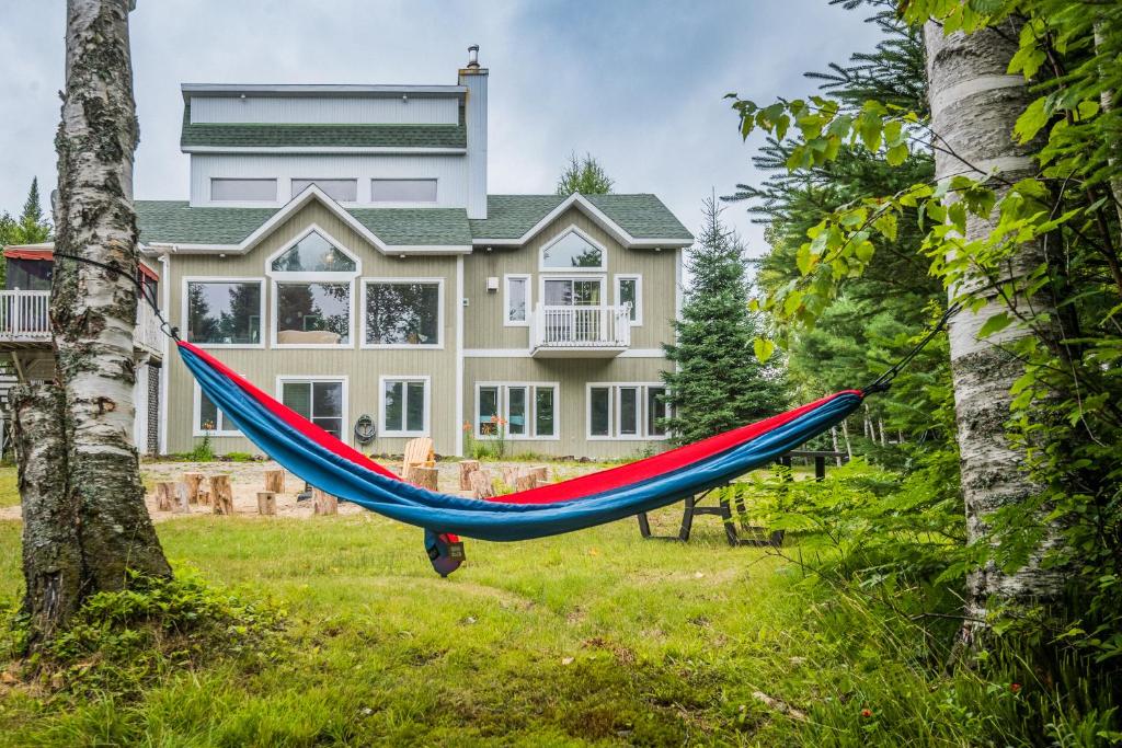 a hammock in front of a large house at Le Chaleureux du Lac Blanc - Nominingue in Nominingue