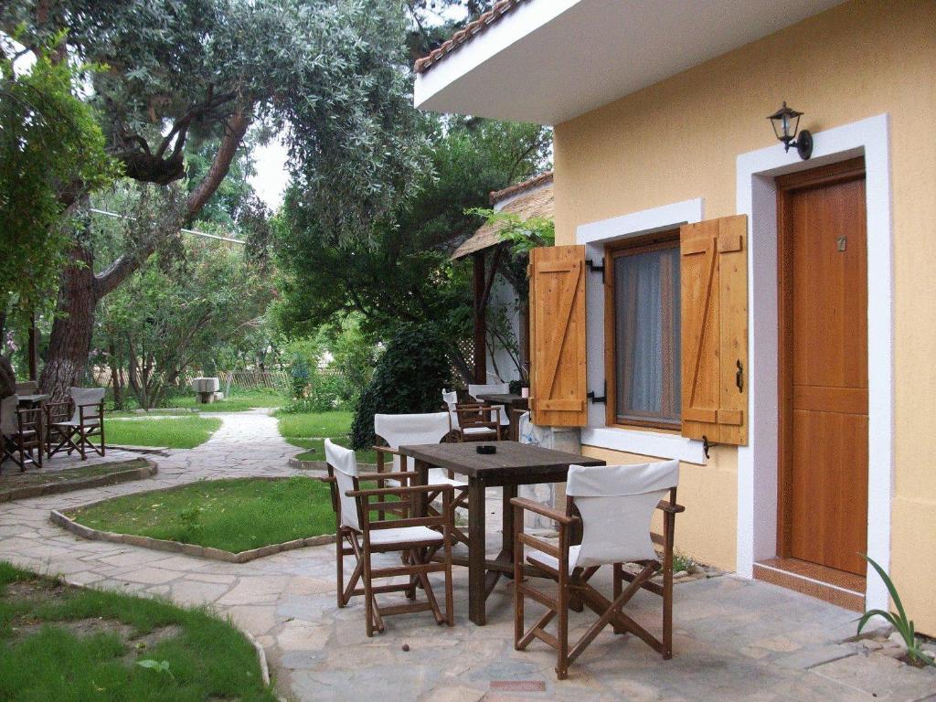 un patio con mesa y sillas junto a una casa en Lysistrata Bungalows, en Potos