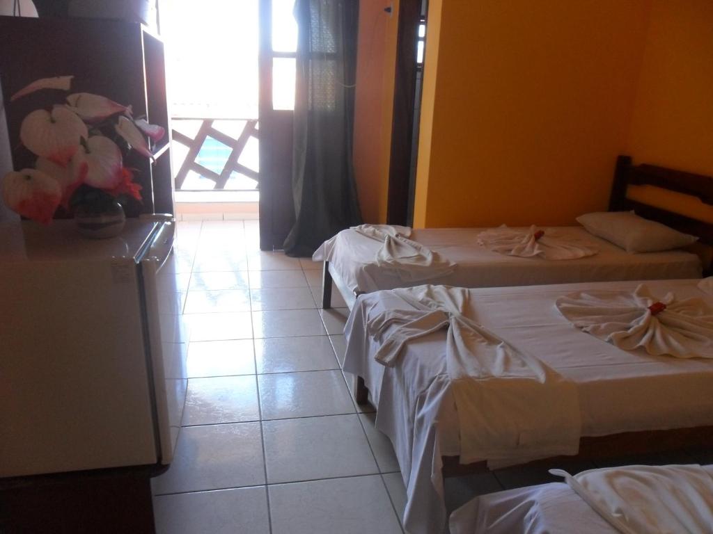 a hotel room with two beds and a window at Hotel Beira Rio Preguiças in Barreirinhas