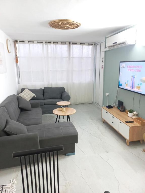 a living room with a couch and a flat screen tv at Levis house Eilat in Eilat