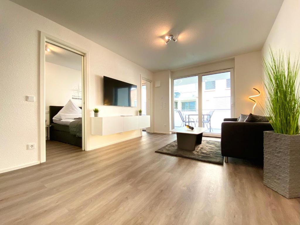 sala de estar con sofá, cama y espejo en Auszeit Apartment STYLE am Uferpark - nur 100 m bis zum Bodensee, direkt am Bodenseeradweg, Sonnenbalkon, schnelles WLAN, kostenloser Tiefgaragenstellplatz, für bis zu 2 Personen, en Friedrichshafen