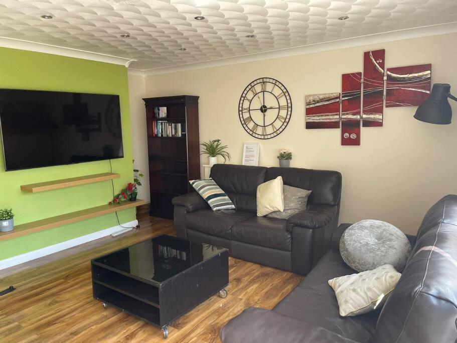 a living room with a couch and a flat screen tv at 5 Bedroom House by monishortlets in Dagenham