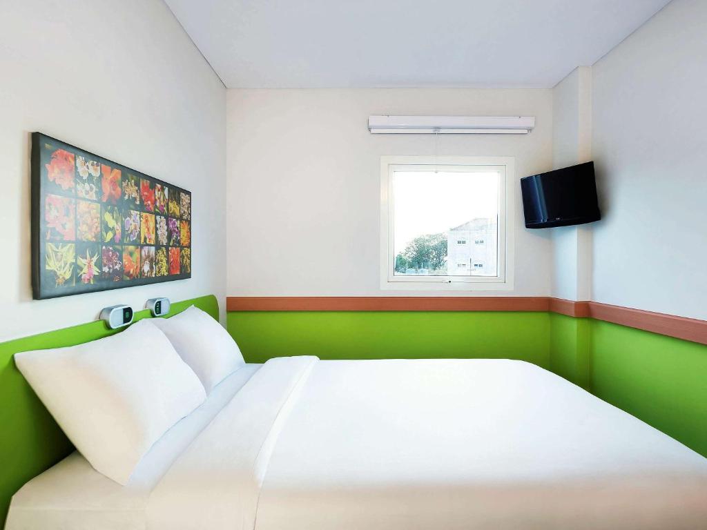 1 dormitorio con cama blanca y ventana en Ibis Budget Semarang Tendean - CHSE Certified en Semarang
