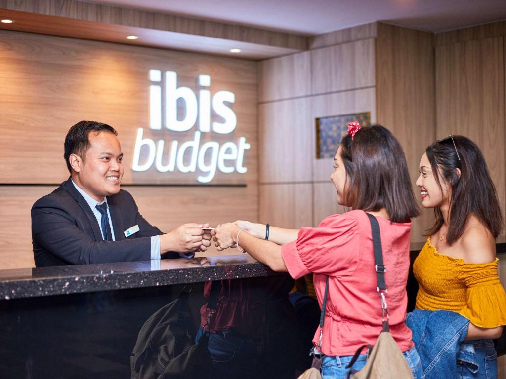 a man and two women shaking hands at a table at ibis budget Singapore Ruby in Singapore