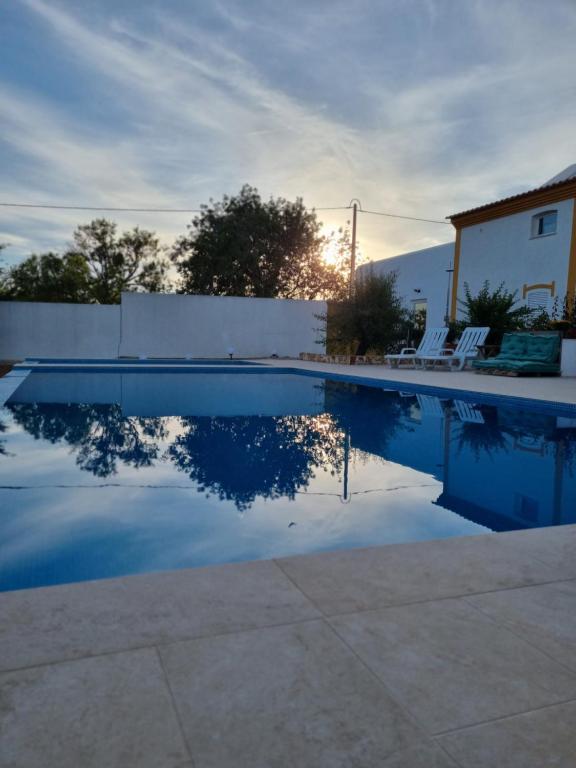 a swimming pool with a fence and chairs and the sky at Villa das Alfarrobas Cosy Guest House in Algoz