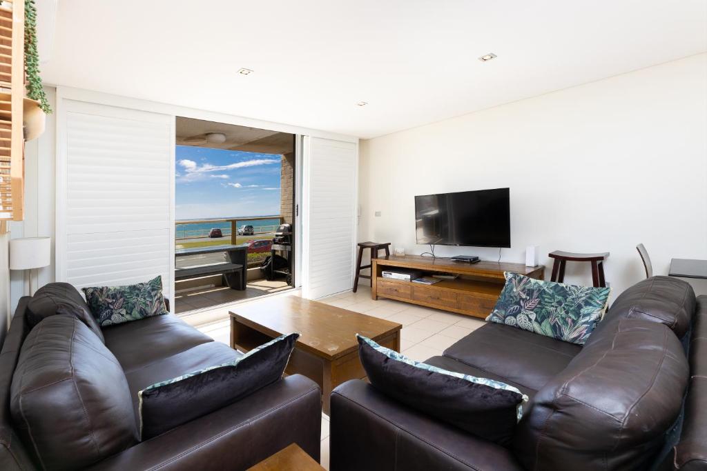 sala de estar con muebles de cuero y TV de pantalla plana en Ebbtide, Unit 04, 2-6 North Street, en Forster
